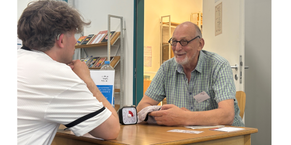 Ein jüngerer und ein älterer Mensch sitzen einander in einer Gesprächssituation gegenüber
